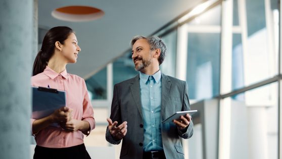 Happy business colleagues talking while walking together through #image_title