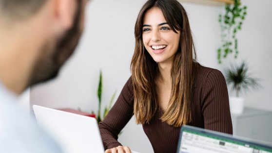 SmilingYoungCoworkersWorkingTogetherWithLaptopInTheOffice #image_title